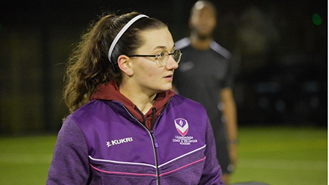 Student standing on a football pitch
